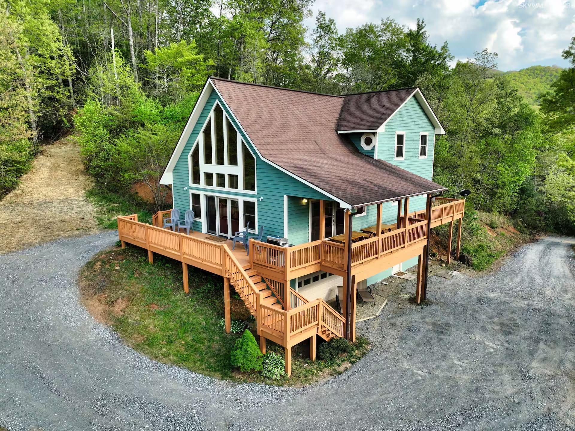 Teal A-frame mountain cabin with fire pit at twilight